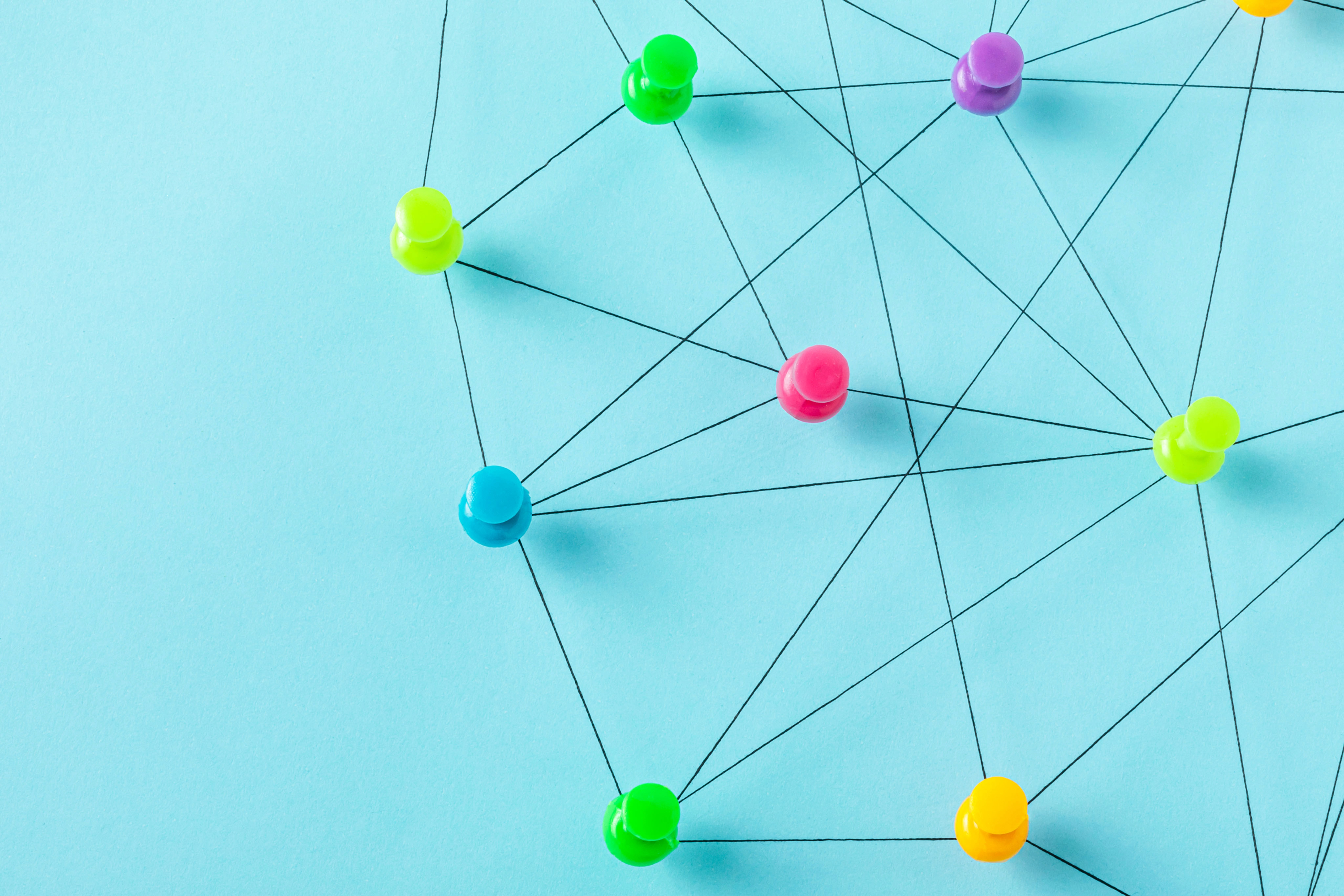 A group of thumbtacks arranged on a blue background, connected by black lines.