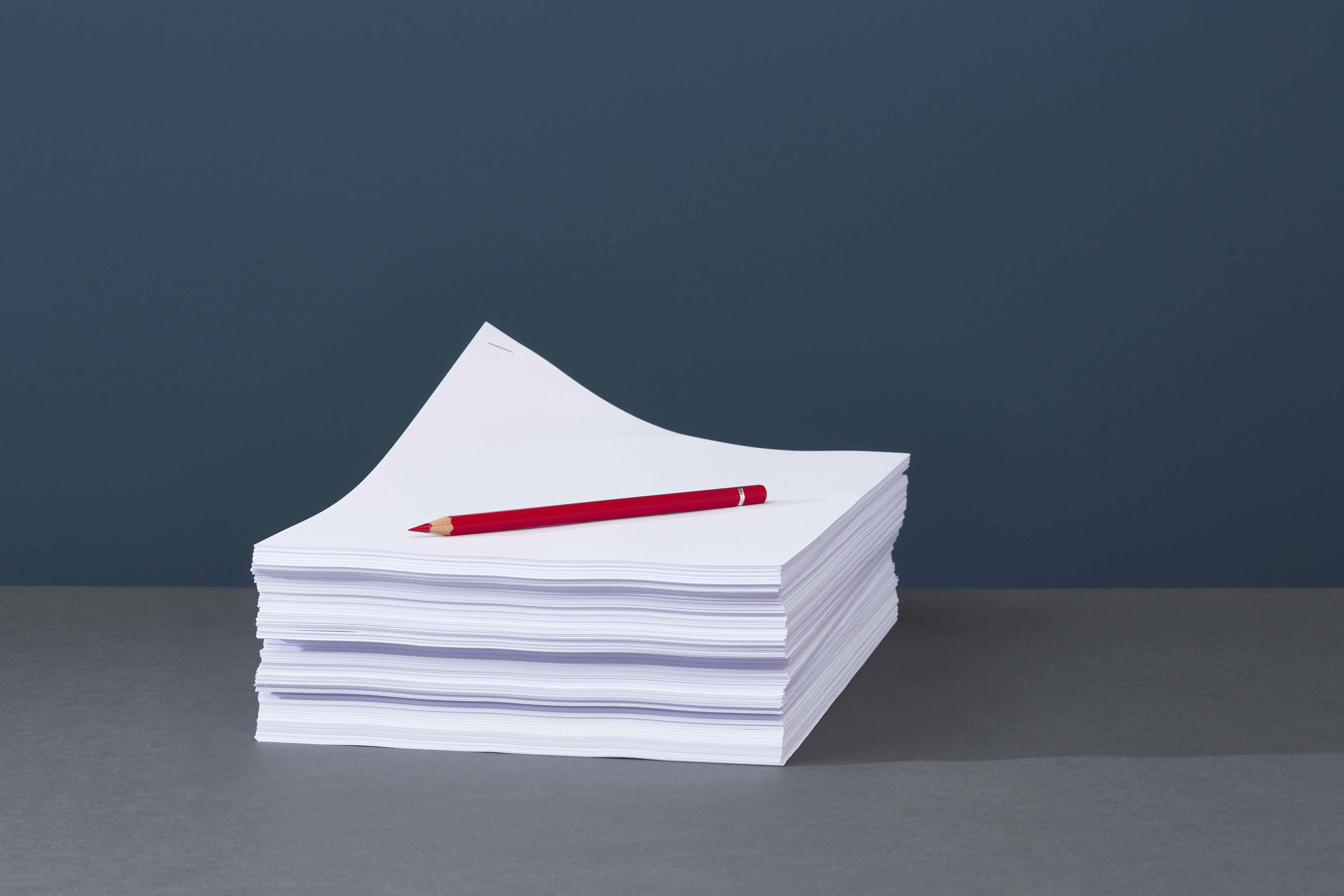 Stack of papers with red pen on top.