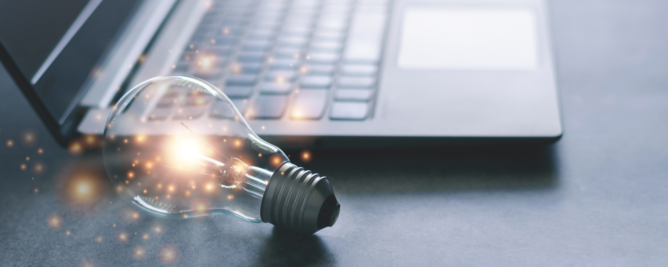 Glowing light bulb next to a laptop computer