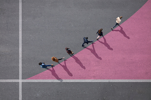 A row of people walking in an upwards diagonal along a line.