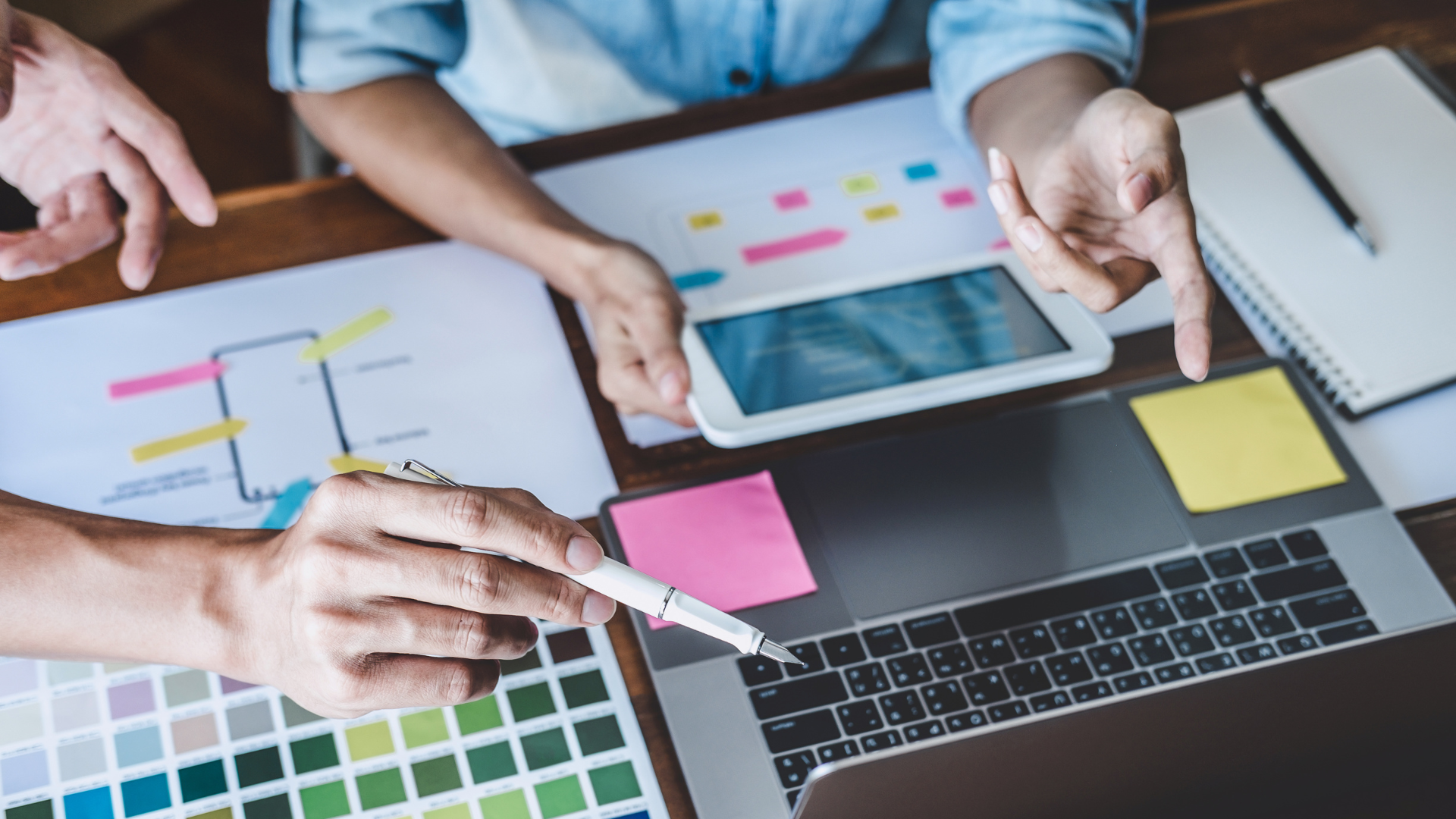 Two people siting at a desk working on branding with paper and computer