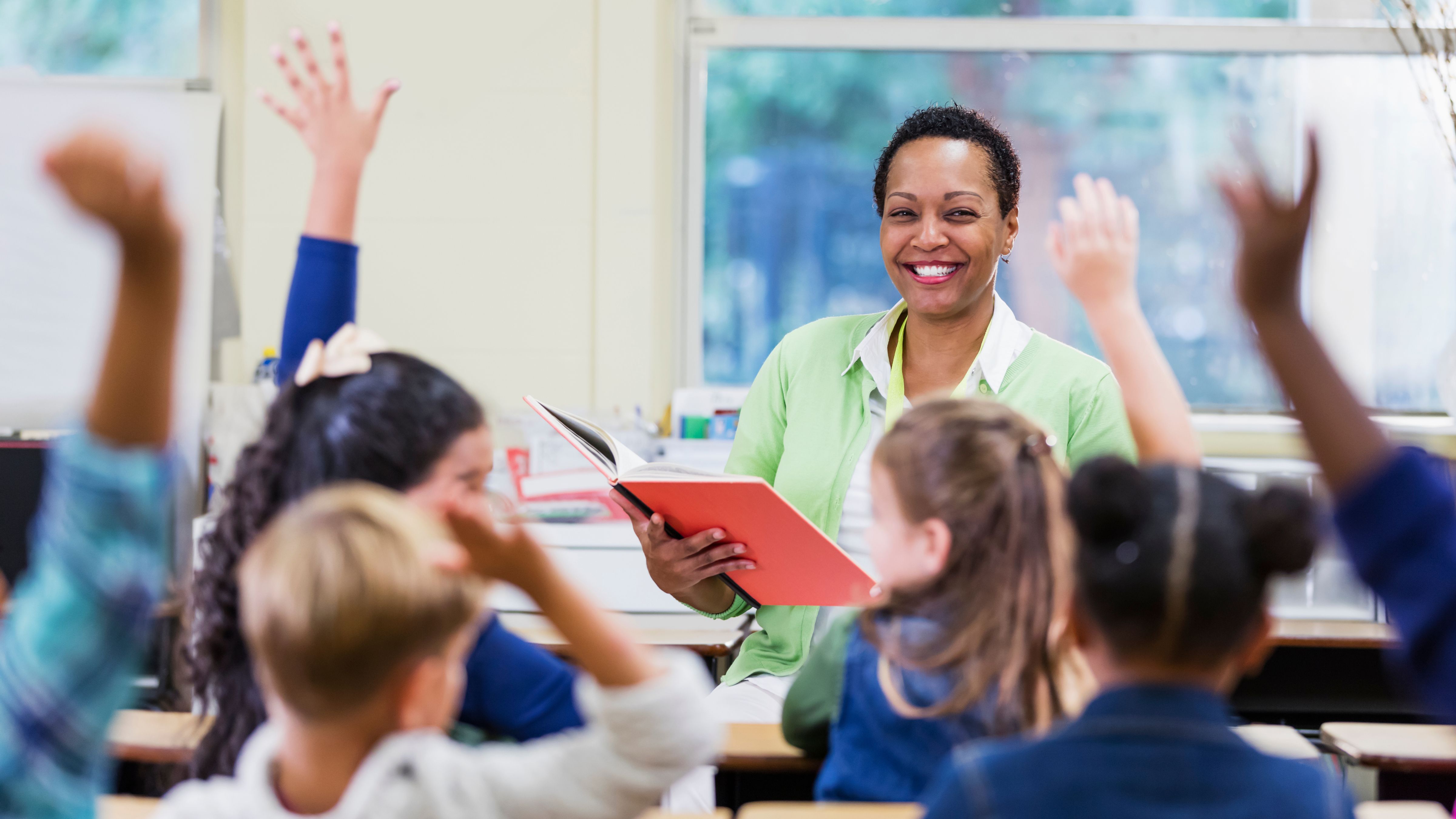 A teacher smiles in front of a eager students in a classroom