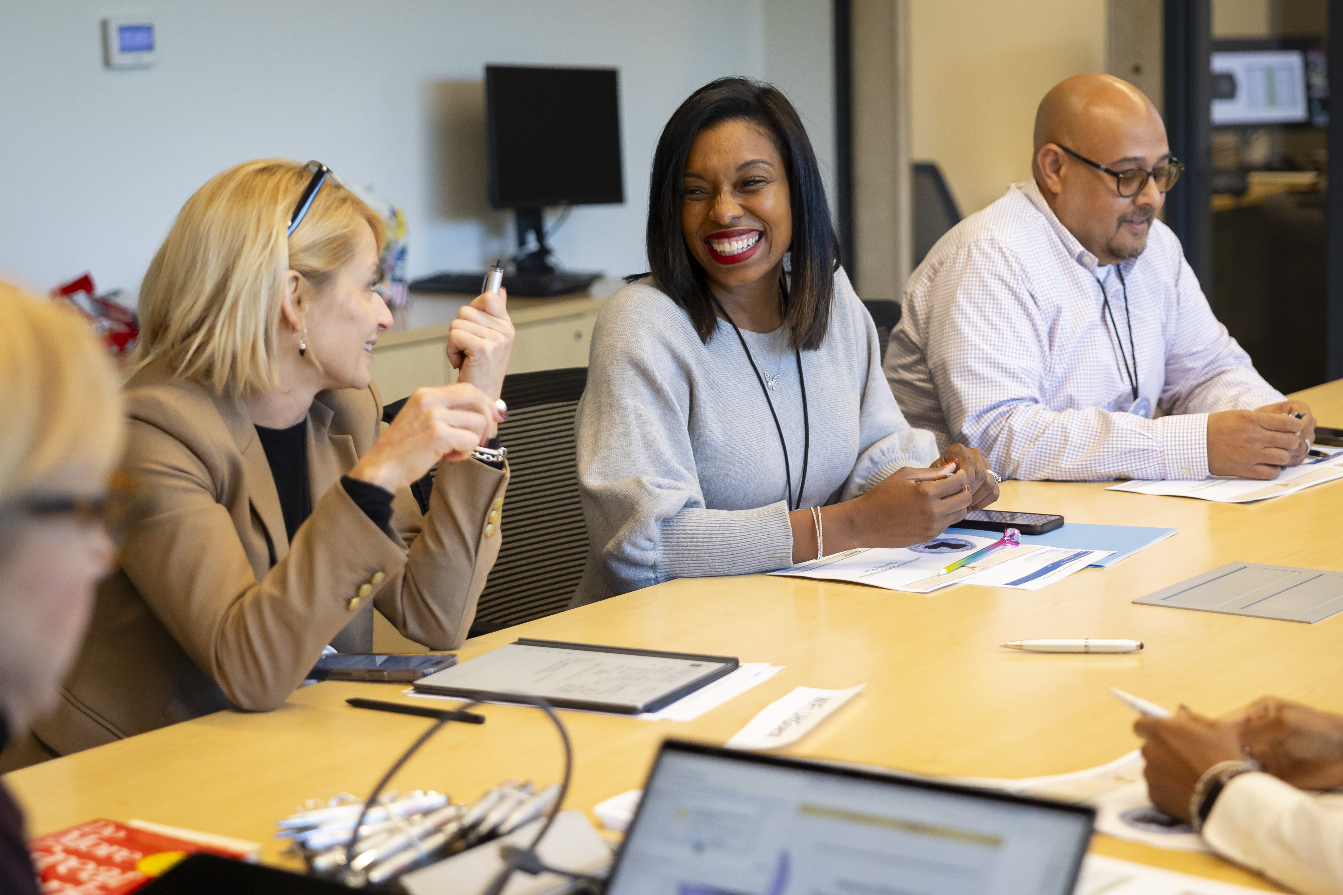 Advisory board members sitting at a table talking and smiling during a meeting