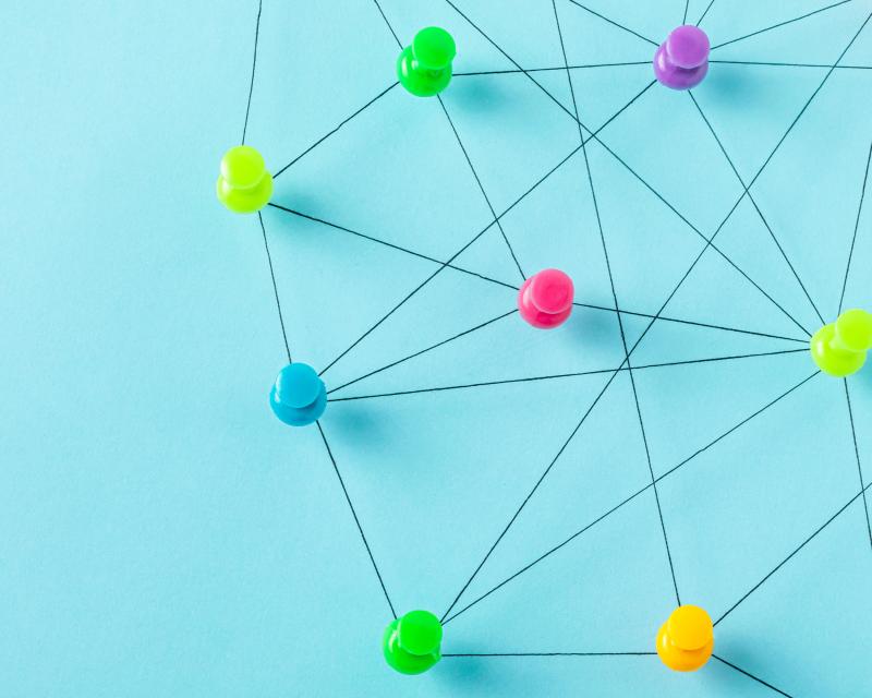 A group of thumbtacks arranged on a blue background, connected by black lines.