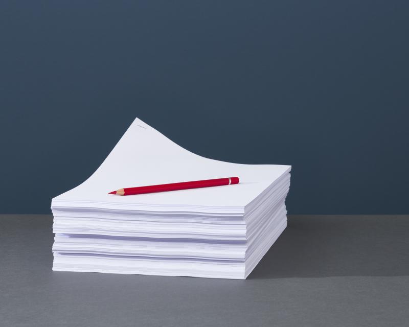 Stack of papers with red pen on top.