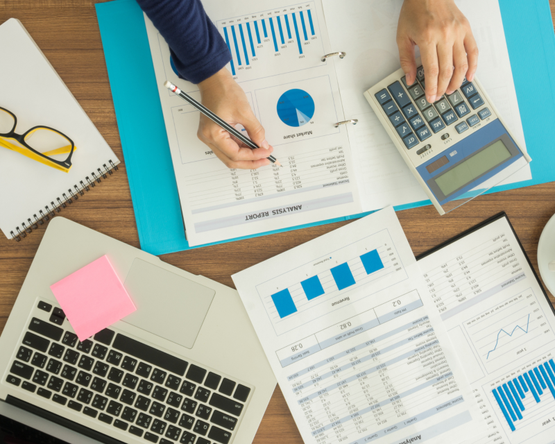 Person at desk using a calculator and reviewing budget documents