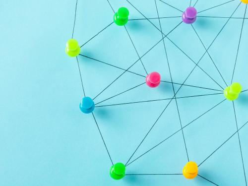 A group of thumbtacks arranged on a blue background, connected by black lines.
