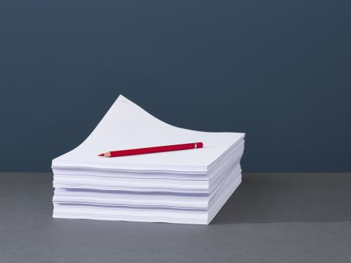 Stack of papers with red pen on top.