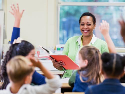 A teacher smiles in front of a eager students in a classroom